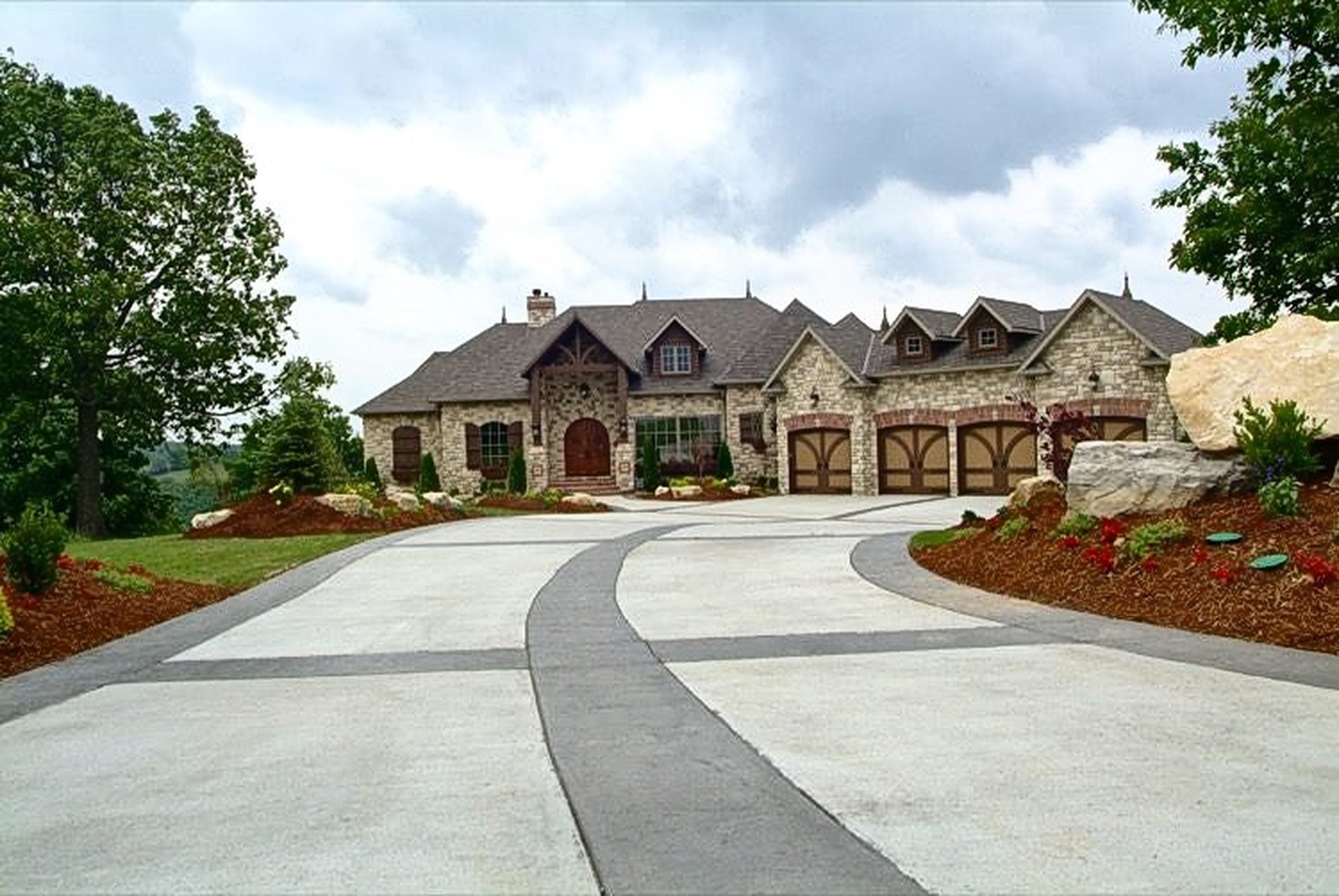 A stone European style home with arched entries and a curved drive