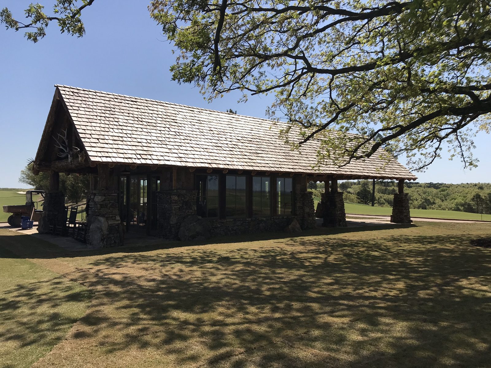 A stone and log timber comfort station with a cedar shake roof on a golf course