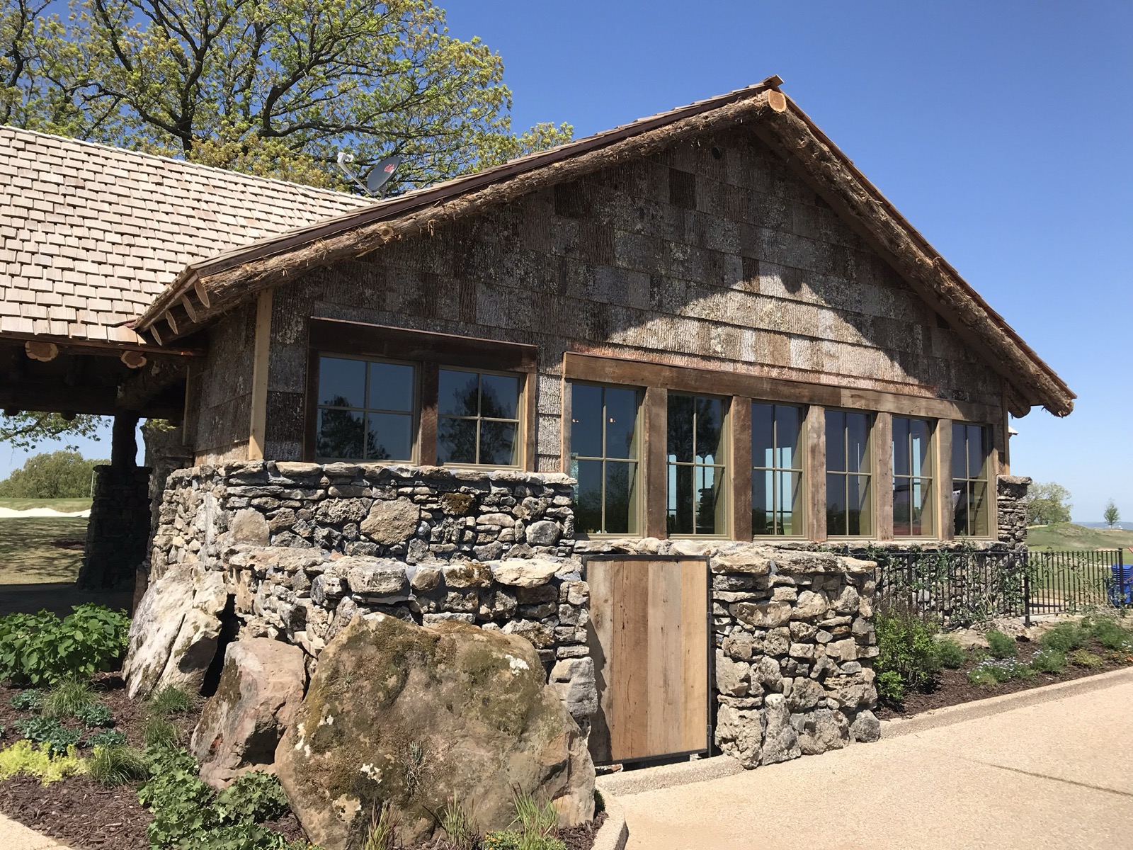 Stone and timber clubhouse building with a cedar shake roof