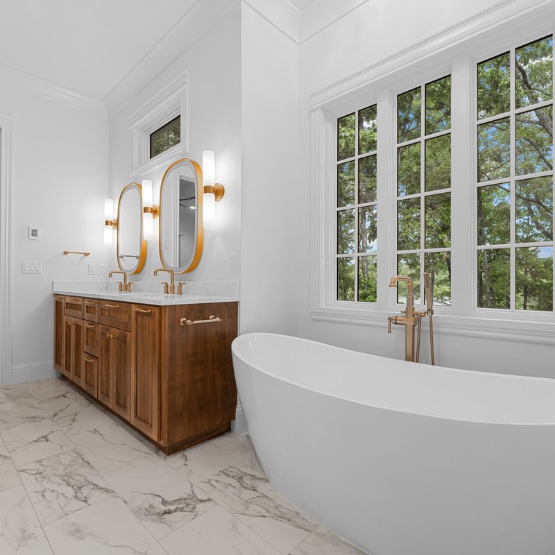 Primary bath with a freestanding tub and a walnut vanity
