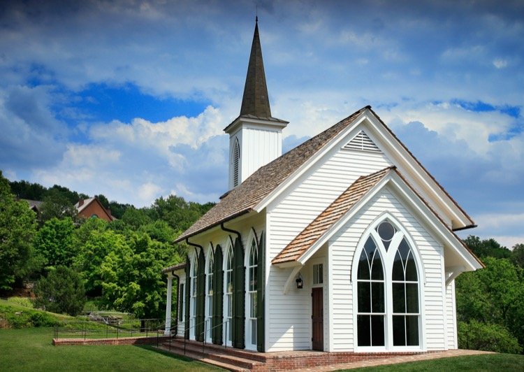 The white Garden Chapel with its steeple against a cloudy Ozarks sky