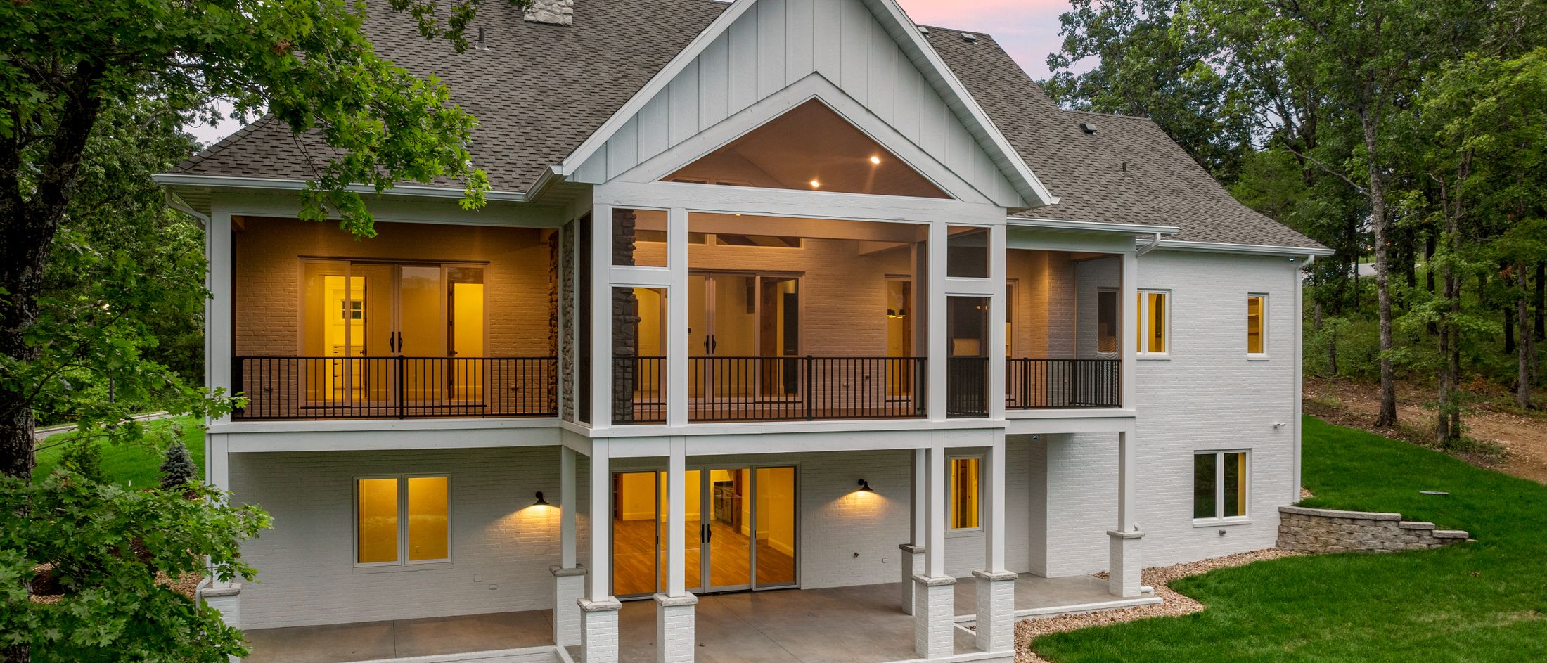 The back of the house at dusk, the covered porches lit