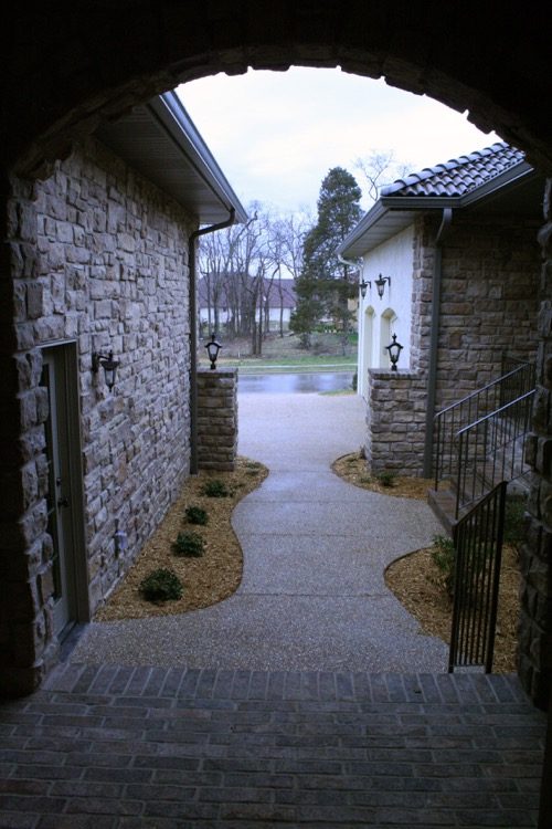 A stone arch walkway into a Tuscan style home