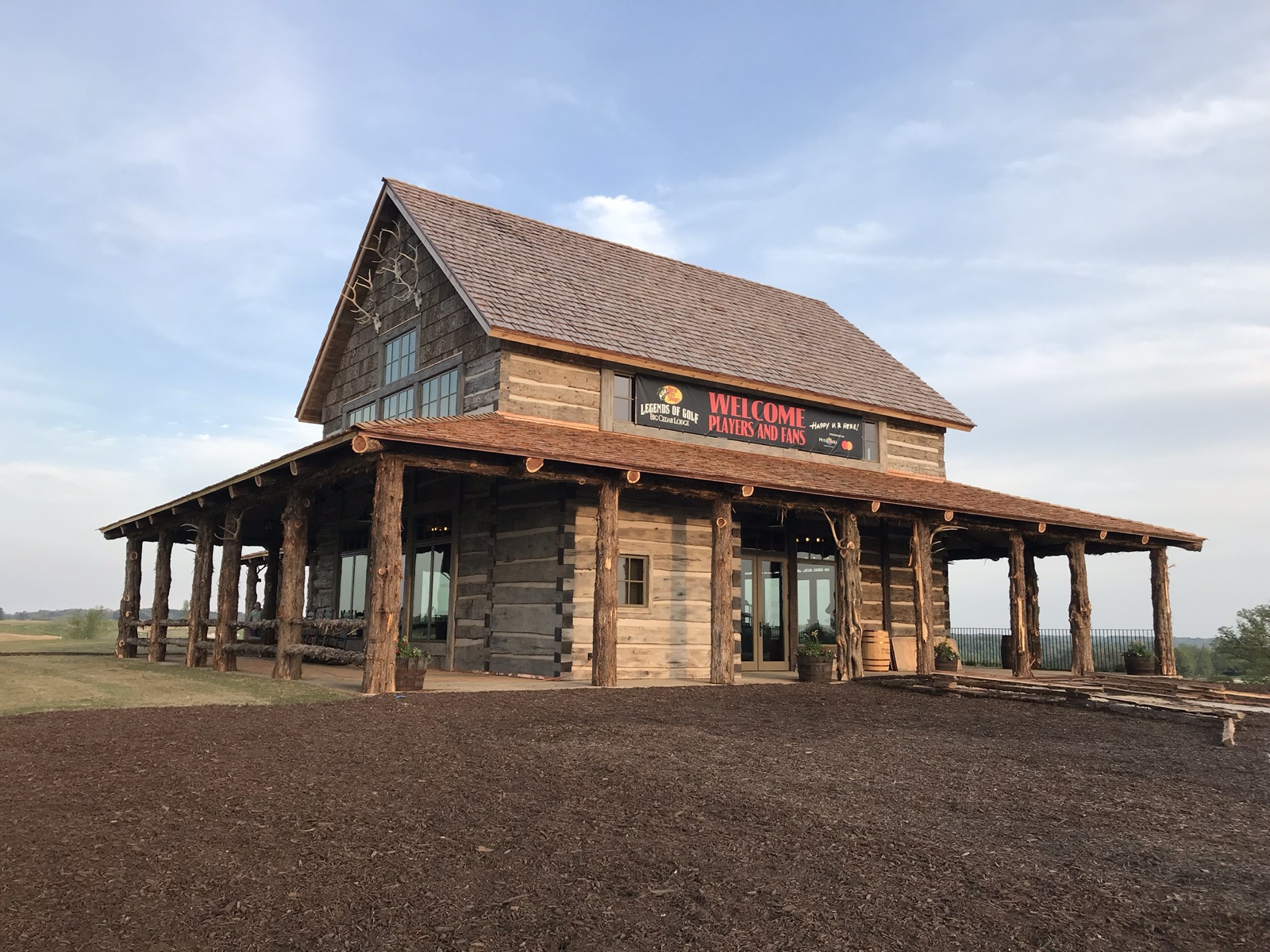 The Ozarks National Pro Shop, a two story log building with a cedar shake roof and a porch on cedar posts