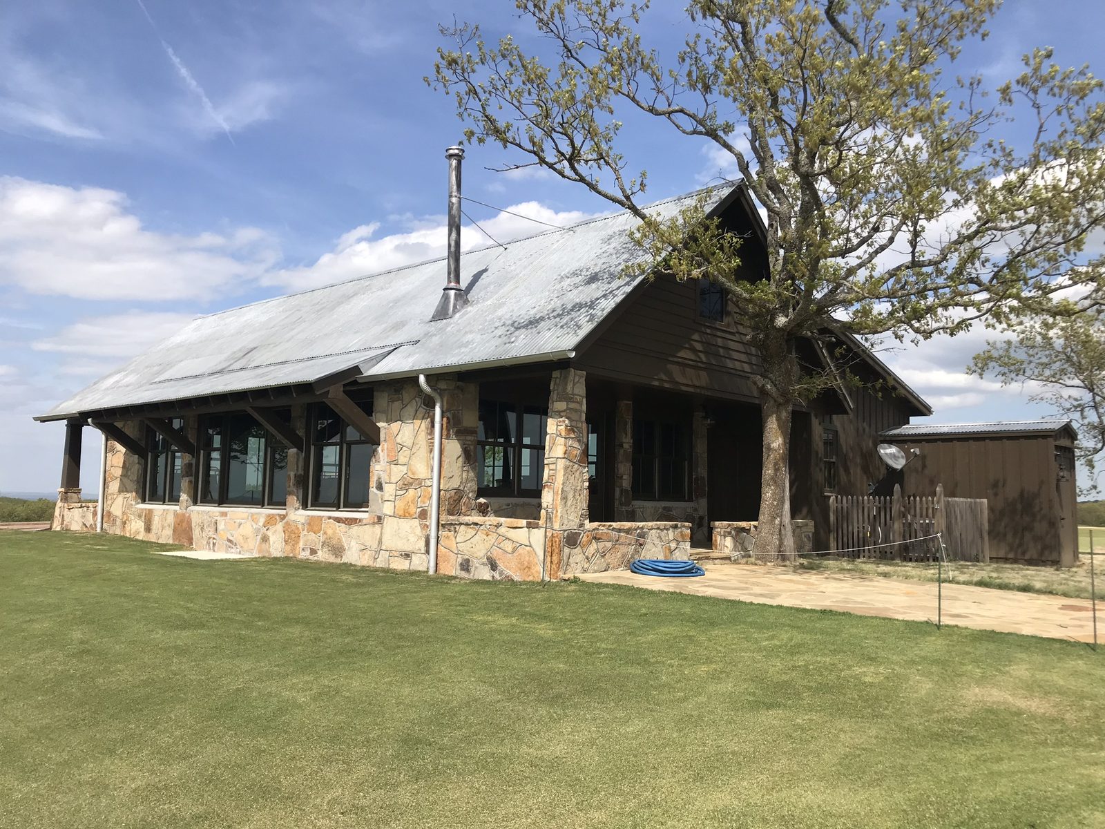 The Stone House at Ozarks National, a timber and stone building under oak trees
