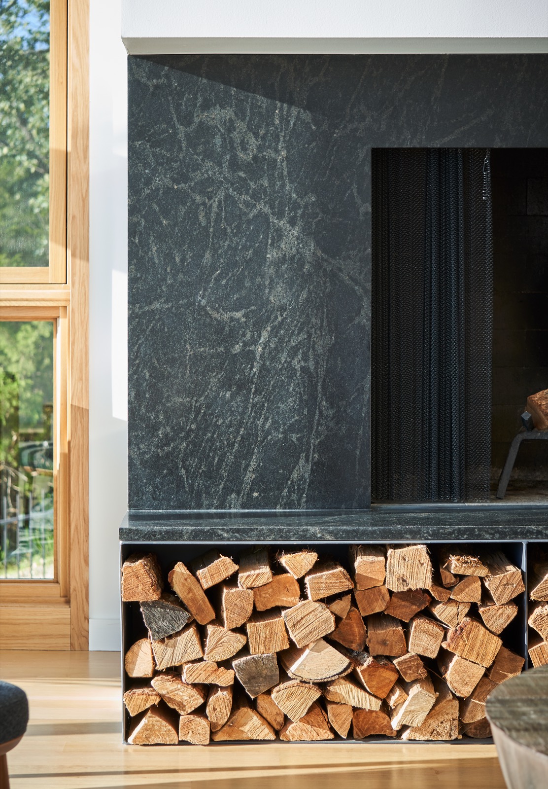 Dark stone fireplace wall with firewood stacked beside it