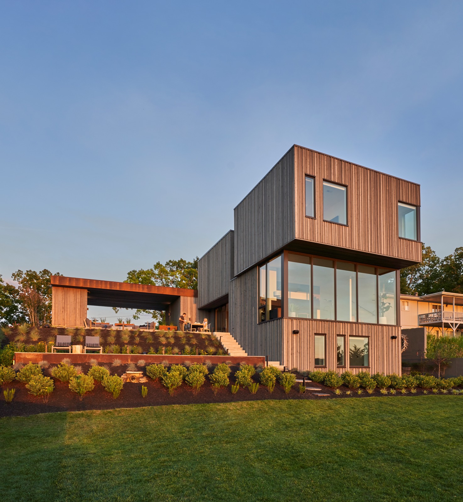 A cedar lake home lit from inside at dusk