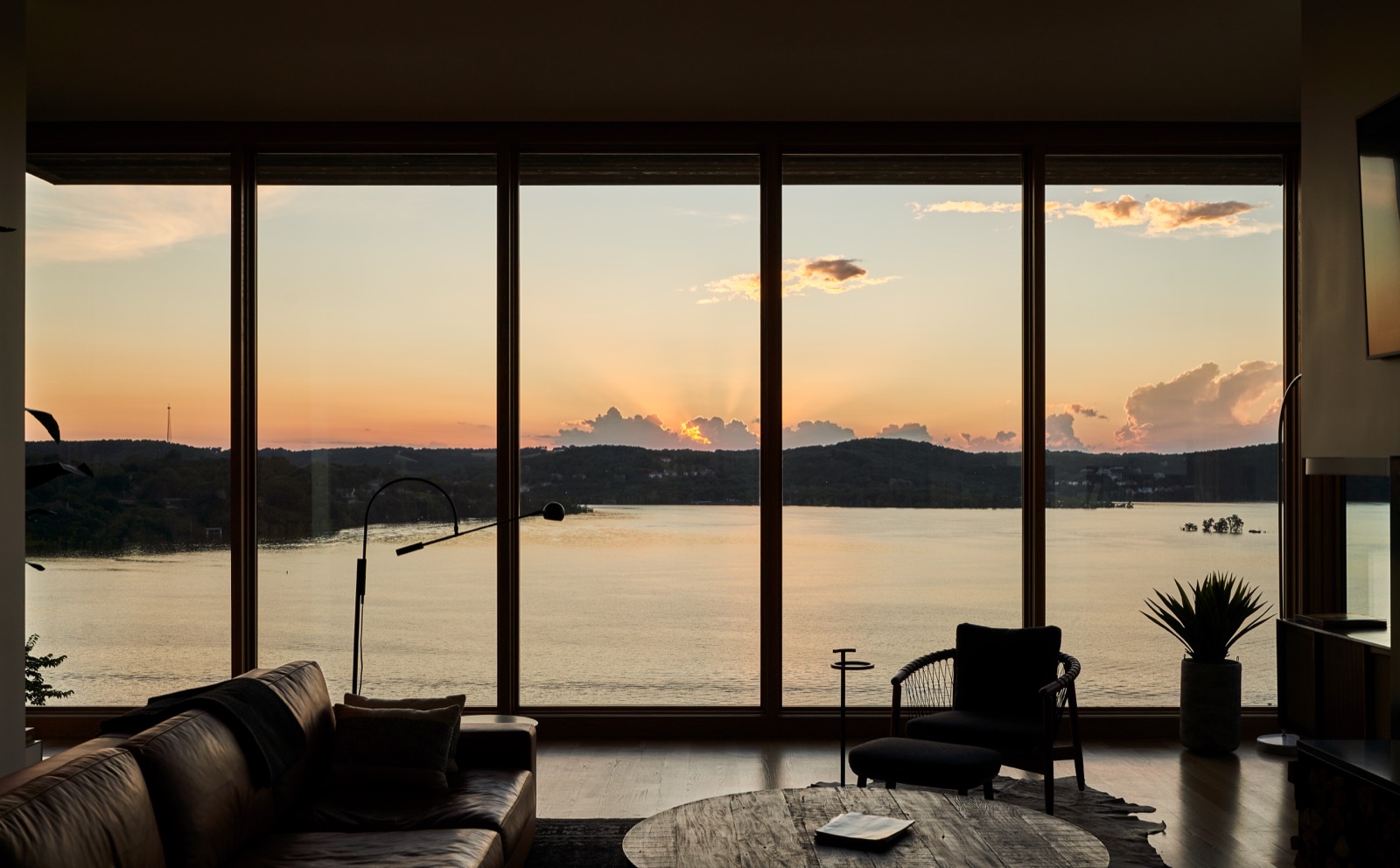 Sunset over the lake seen through the glass wall of the living room