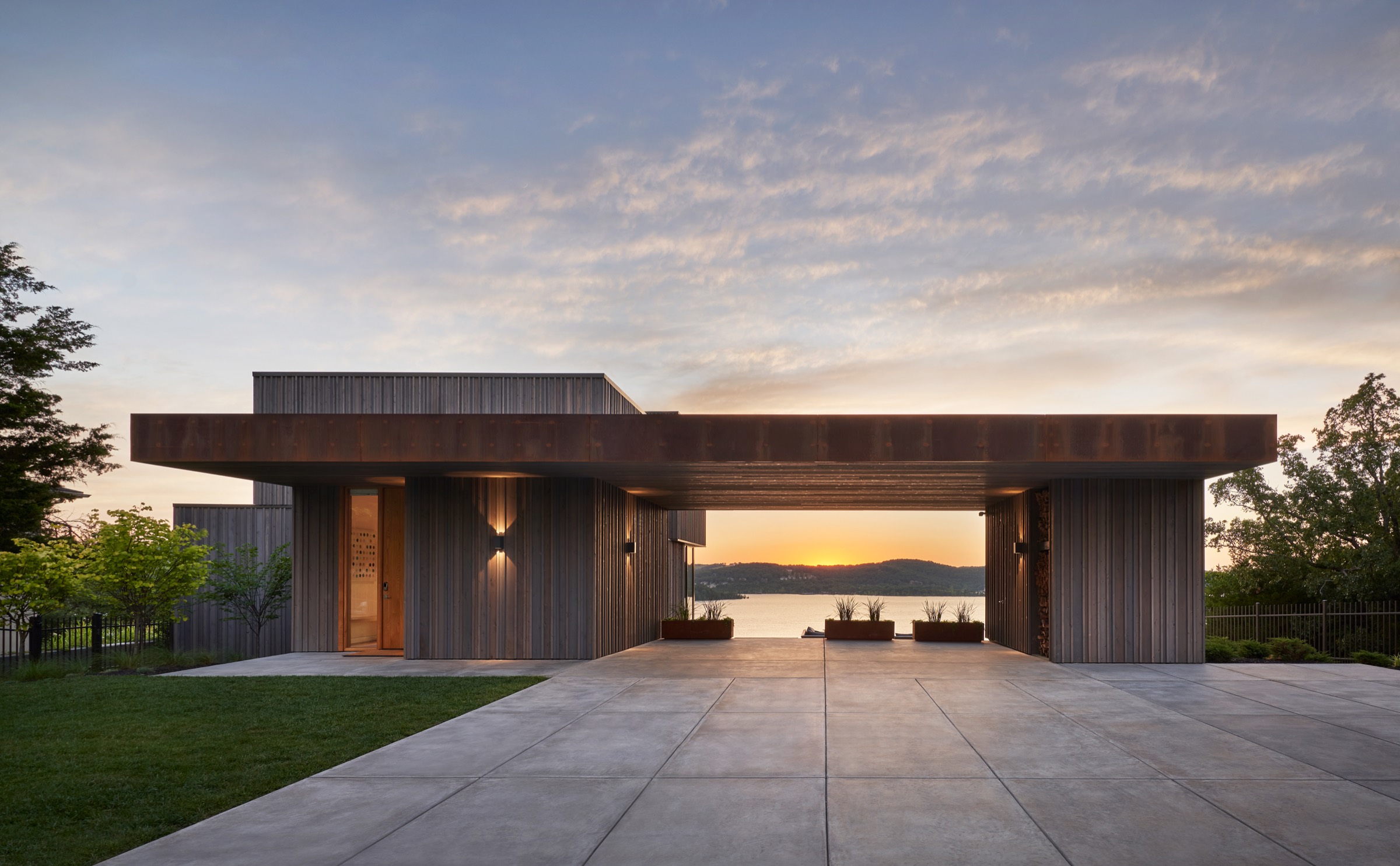 A cedar and steel home on Table Rock Lake at sunset, with the lake framed through an open breezeway